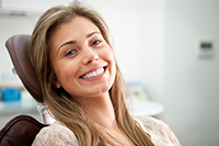 A smiling nearby Jupiter female patient sitting in a dental chair at the office of Roy C. Blake III, DDS, MSD, Maxillofacial Prosthodontist in Jupiter
